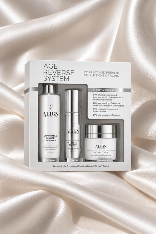ALIGN Age Reverse System skincare set in a white box, featuring a cleanser, serum, and cream, displayed on a draped champagne satin fabric background.