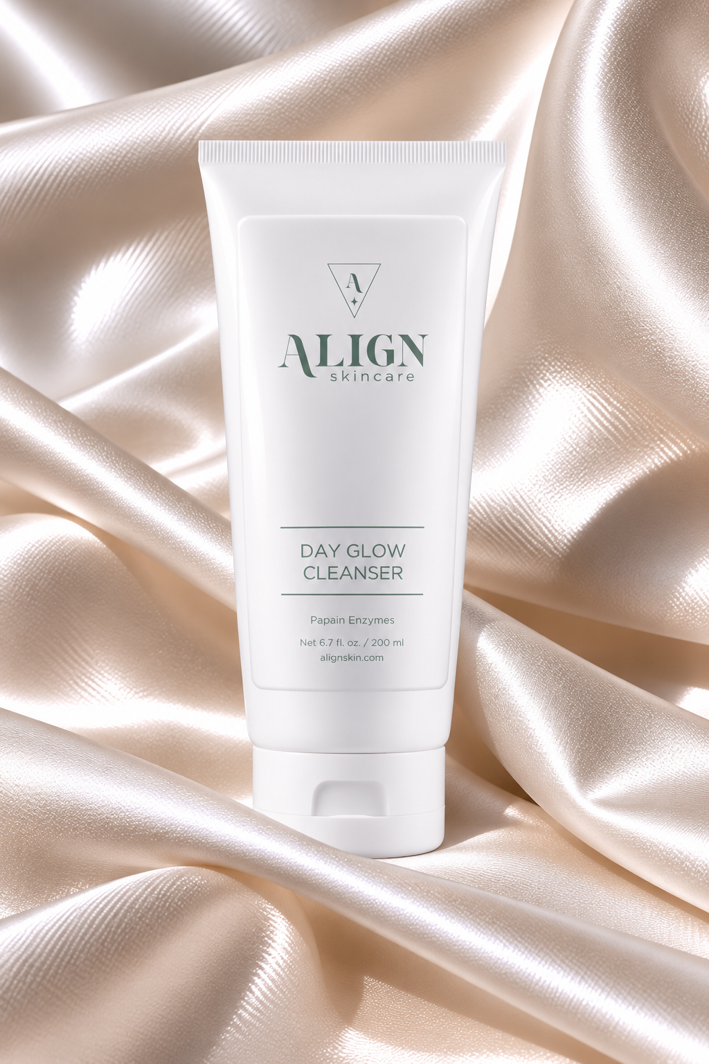 A white tube of ALIGN skincare Day Glow Cleanser standing upright on draped champagne satin fabric.