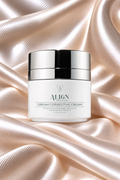 ALIGN Skin Care Dream Corrective Cream in a white jar with a shiny silver lid, set against a luxurious draped satin fabric background in a soft champagne color.