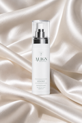 A white cylindrical skincare pump bottle labeled ALIGN SKINCARE VITA MIST, standing upright on draped champagne satin fabric.